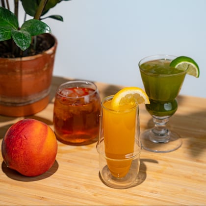 Bright display of iced tea cocktails with lemon and lime slices and a peach